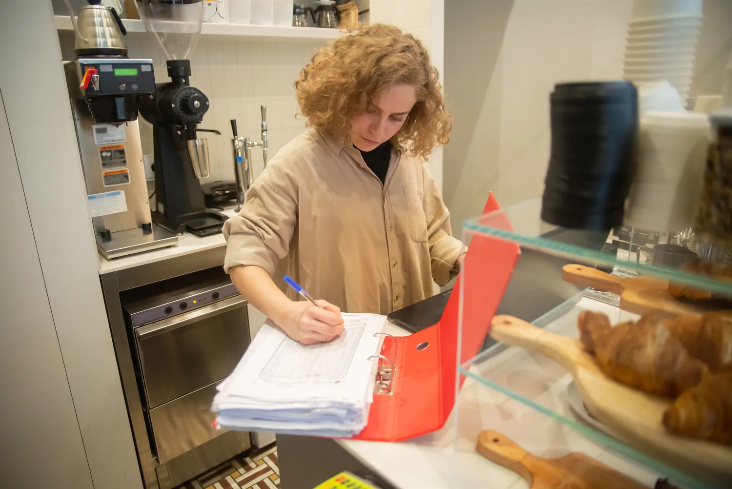 A café worker checking paperwork at a kitchen counter